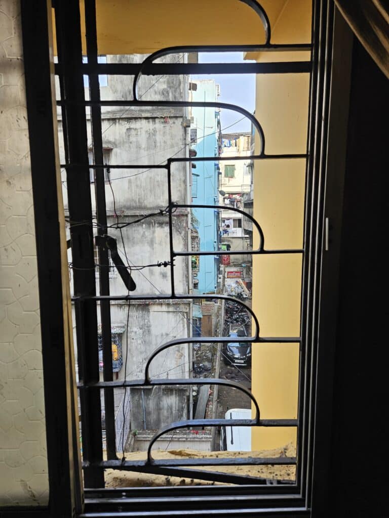 A view from inside an orphanage. Looking out through bars on the window to other buildings and a narrow back street in the city of Kolkata. Children living with deafness often end up in institutions like this.