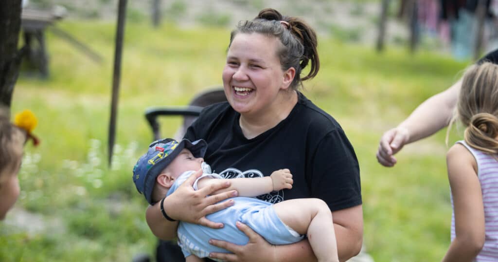 Tina* laughing joyfully with baby Serhii* in her arms, Ukraine.