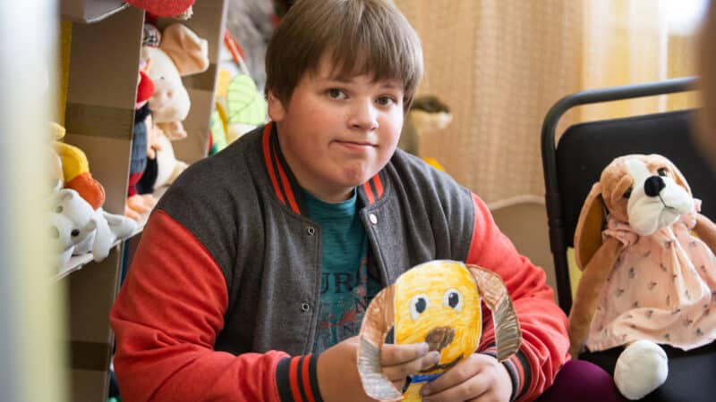 Andrii*, a Ukrainian boy with autism, clutches his drawing of a hibuki dog