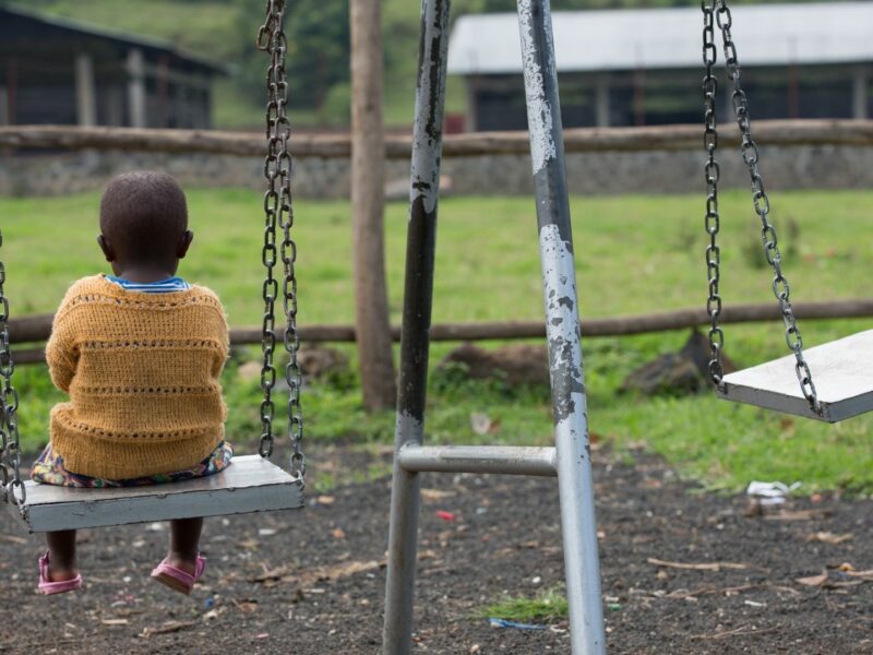 A picture of a child sitting on a swing alone, from our programmes in Rwanda