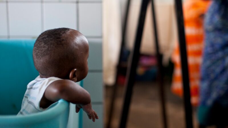 A baby leaning out of a plastic blue tub