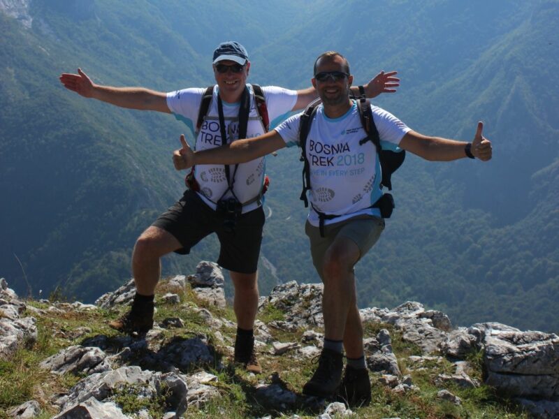 Two friends standing on the top of a mountain during a fundraiser