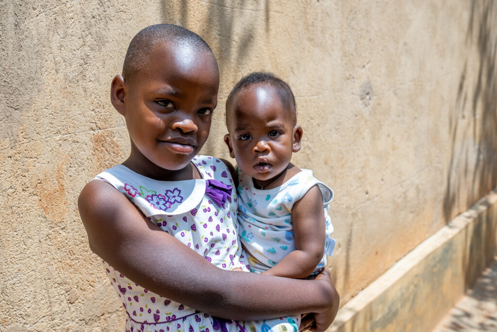 Young Rwandan care leaver holds her sister in her arms, now she has a family to be part of