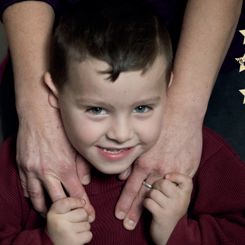 Young boy smiling holding hands with his parent