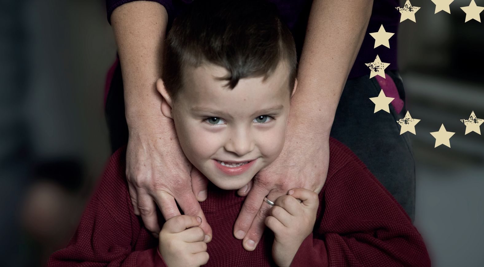 Young boy smiling holding hands with his parent