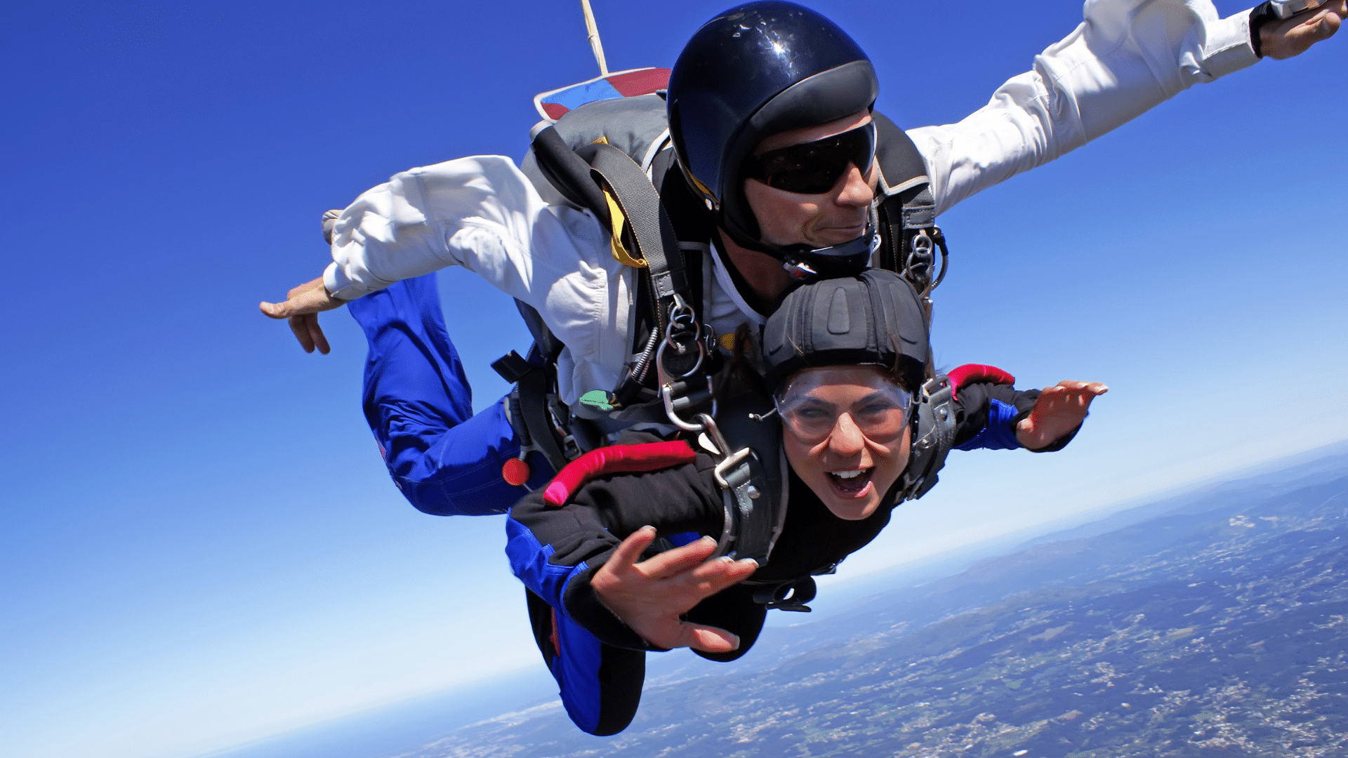 Skydiver happily freefalling through the blue sky, attached to an instructor
