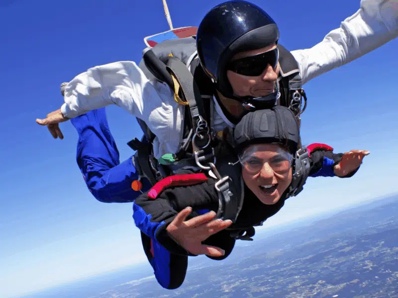 Skydiver happily freefalling through the blue sky, attached to an instructor